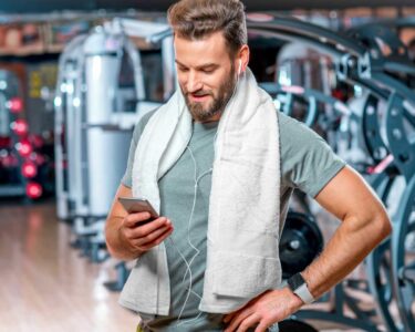 Mężczyzna na siłowni sprawdzający informacje o suplementach na smartfonie