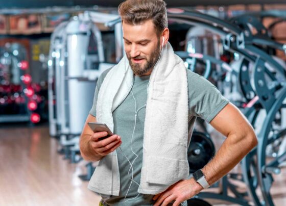 Mężczyzna na siłowni sprawdzający informacje o suplementach na smartfonie