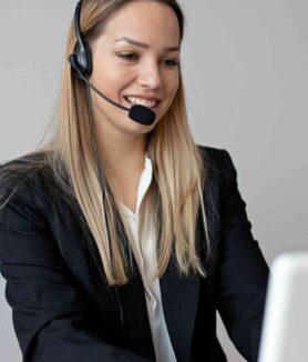 Konsultantka obsługi klienta w słuchawkach z mikrofonem, pracuje przy laptopie