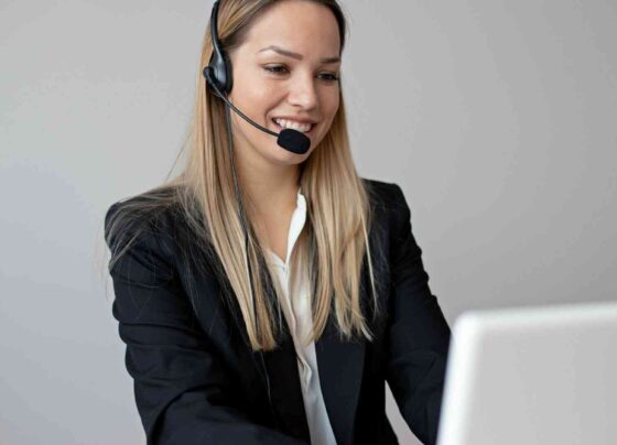 Konsultantka obsługi klienta w słuchawkach z mikrofonem, pracuje przy laptopie