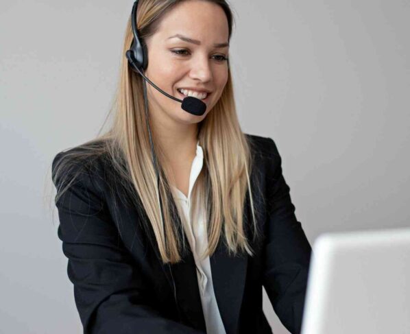 Konsultantka obsługi klienta w słuchawkach z mikrofonem, pracuje przy laptopie